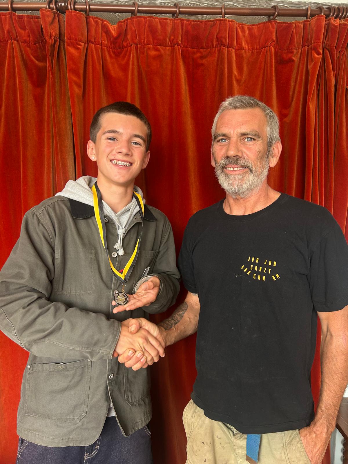 Stan shaking hands and holding his personalised 5asideCHESS Connect 25 medal
