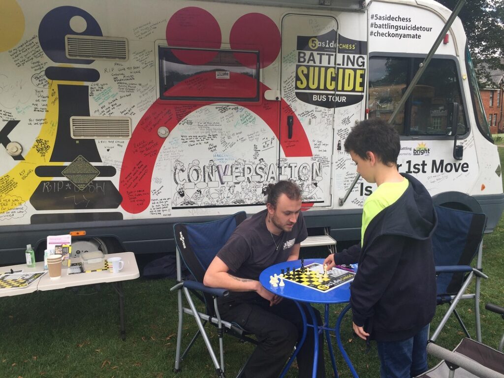 A game of chess beside the signature-covered Battling Suicide Bus in Donegal Town